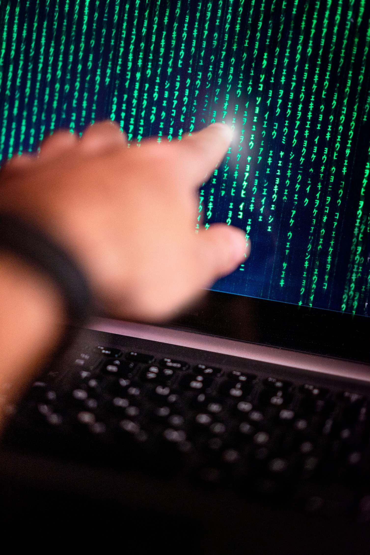 Developer workstation with code on screen, person points at glowing code on a computer screen