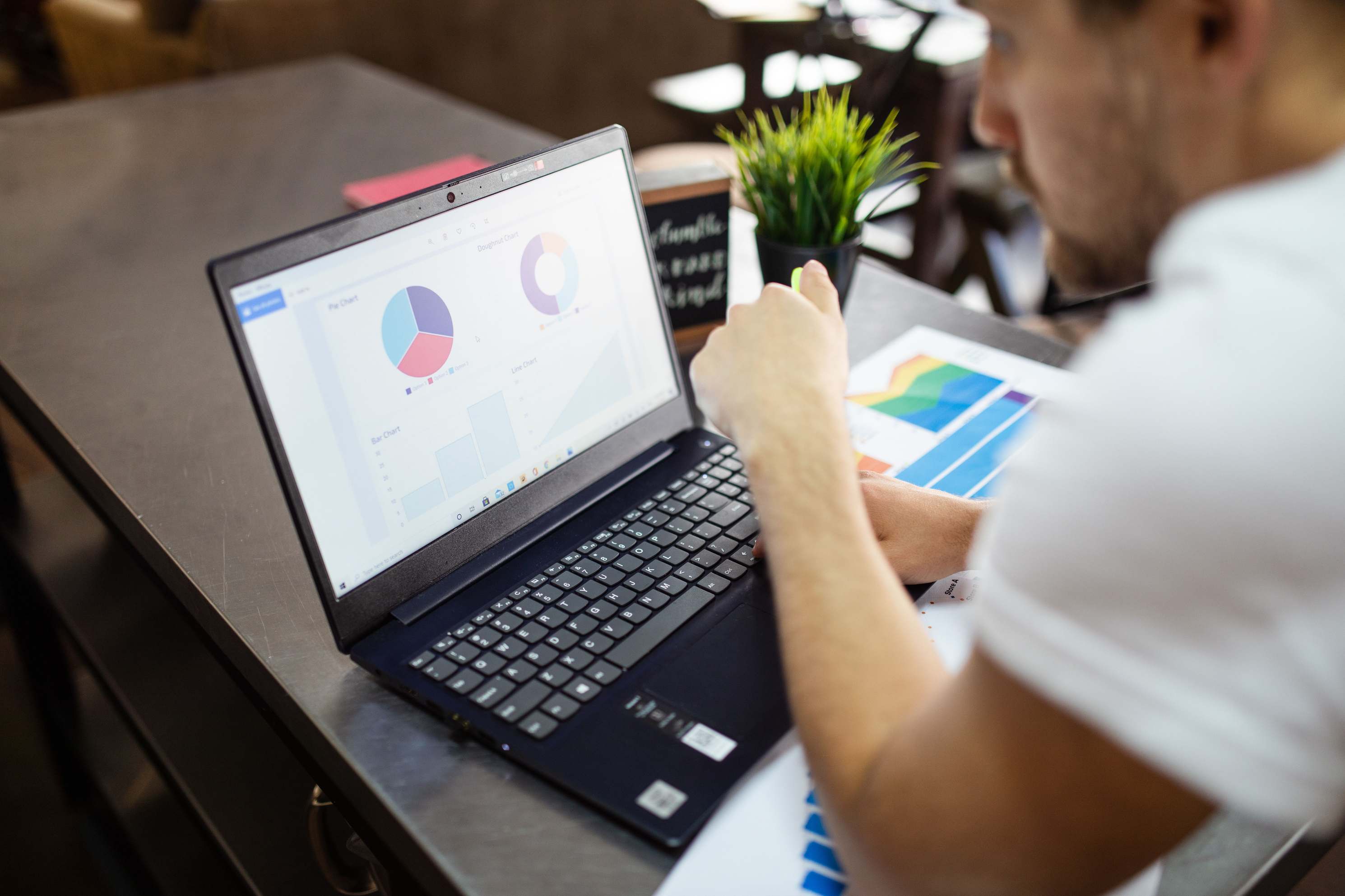Laptop showing monitoring graphs on a desk, person reviewing charts and graphs on a laptop
